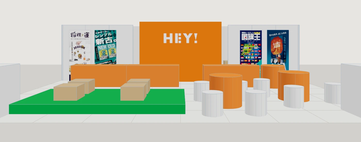 通路から見た HEY! のブース。中央にオレンジの HEY! ロゴ、左右にコロコロ将棋・ニューオールド・国旗王・マッチ売りの大富豪のポスター
